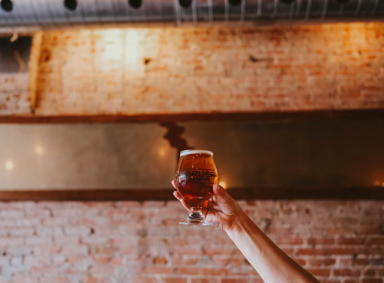 Customer holding up a Border Brewing beer with pride
