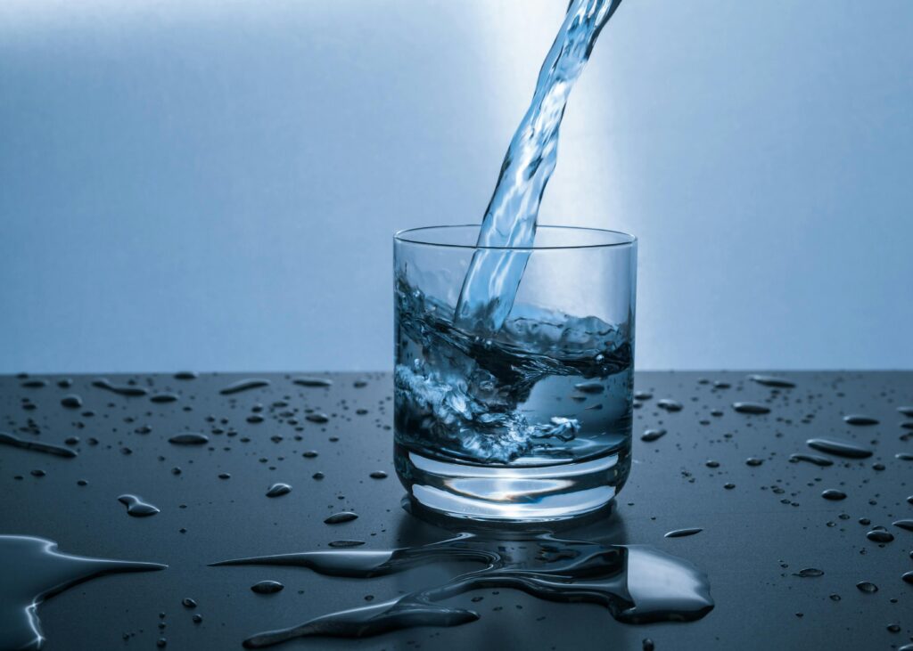 A glass of water being poured on a shiny table surface