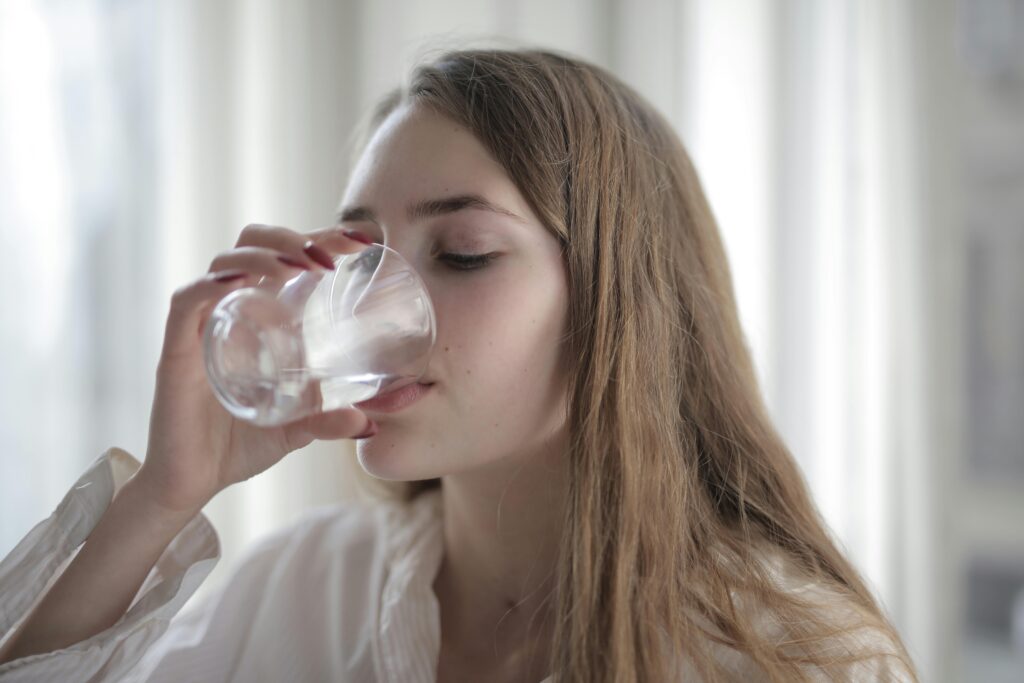 A young woman drinking tap water from a glass