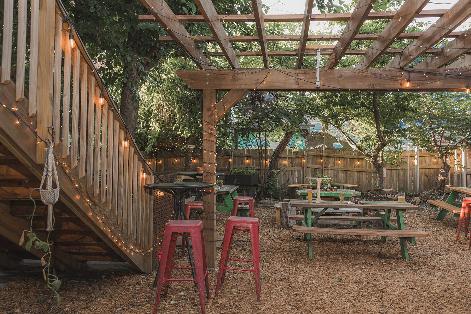 The pergola and staircase at the edge of the Border Brewing patio with high-top stools underneath