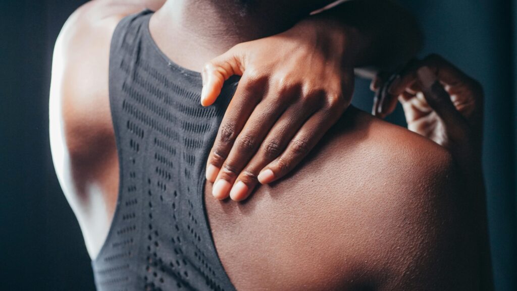 African American woman with hand on her back to show signs of pain and inflammation.